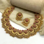 Gold plated South Indian choker necklace set with earrings featuring red stones and temple jewelry design.
